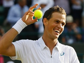 Vasek Pospisil of Canada holds a ball as he celebrates defeating James Ward of Britain during their singles match at the All England Lawn Tennis Championships in Wimbledon, London, Saturday July 4, 2015. Pospisil won the match 6-4, 3-6, 2-6, 6-3, 8-6. (AP Photo/Kirsty Wigglesworth)