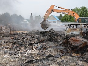 Andre Belisle, mayor of Saint-Sixte, takes to the controls of the excavator to aid in the extinguishing of molten debris at the site of Monday's fire north of Thurso, Que. on Tuesday, July 7, 2015. SAM COOLEY/OTTAWA