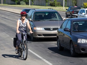 A cyclist rides westbound in a bike lane along 95 Avenue at 178 Street next cars in Edmonton, Alta., on Tuesday July 7, 2015. The Edmonton city council members are debating keeping the lane, which runs from 142 Street to 189 Street along 95 Avenue. Ian Kucerak/Edmonton Sun/Postmedia Network