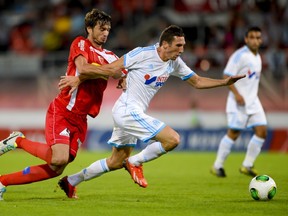 Sion's Beg Ferati (L) vies with Marseille's Morgan Amalfitano (C) during their match at the Valais Cup football tournament on July 9, 2013 in Sion.  AFP PHOTO / FABRICE COFFRINI