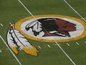 FILE - In this Aug. 7, 2014 file photo, the Washington Redskins logo is seen on the field before an NFL football preseason game against the New England Patriots in Landover, Md.  A federal judge has ordered the Patent and Trademark Office to cancel registration of the Washington Redskins' trademark, ruling that the team name may be disparaging to Native Americans. The ruling Wednesday by Judge Gerald Bruce Lee affirms an earlier finding by an administrative appeal board.  (AP Photo/Alex Brandon)