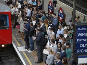 Commuters at Earls Court underground station, awaiting the arrival of a train, attempt to complete their journey on Wednesday evening, in London, Britain, July 8, 2015. A strike by staff and drivers on London's underground train network later on Wednesday, which is set to chaos travel misery for millions of commuters, is "unacceptable and unjustified", a spokesman for Prime Minister David Cameron said.  REUTERS/Peter Nicholls