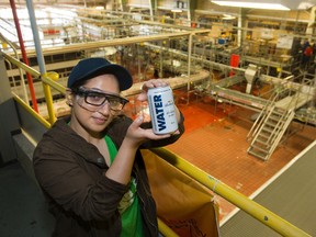 Business process manager Neha Dahr displays one of 264,000 cans of drinking water Labatt Brewery is donating to residents and firefighters in areas affected by forest fires in Saskatchewan, Alberta and British Columbia. The water was canned at the Labatt Brewery in London. (DEREK RUTTAN, The London Free Press)