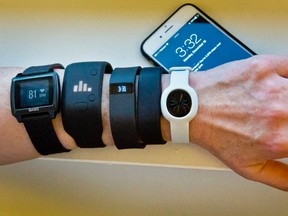 In this Dec. 15, 2014, file photo, fitness trackers, from left, Basis Peak, Adidas Fit Smart, Fitbit Charge, Sony SmartBand, and Jawbone Move, are posed for a photo next to an iPhone, in New York. Although sales of fitness trackers are strong, many of their owners lose enthusiasm for them once the novelty wears off. (AP Photo/Bebeto Matthews, File)