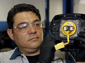 Technician Edward Bonilla holds a recalled Takata airbag inflator after he removed it from a Honda Pilot at the AutoNation Honda dealership service department in Miami, Florida June 25, 2015. The yellow circular device is the airbag inflator. The head of Japan's Takata Corp said an internal probe into its potentially deadly air bag inflators was not progressing well, but vowed to stay at the helm until trust in the safety of its products was restored.  REUTERS/Joe Skipper