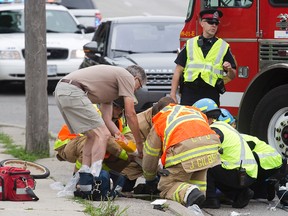 Paramedics and firefighters tend to a female cyclist that was struck by a transport truck on Highbury Ave. just north of Brydges St. in London, Ont. on Wednesday July 8, 2015.  (DEREK RUTTAN, The London Free Press)