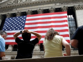 People sit on a bench near the New York Stock Exchange, Wednesday, July 8, 2015. Hong Kong's main stock index plummeted as much as 8.5 percent on Wednesday as a sell-off in mainland Chinese shares accelerated despite new measures to support the market. U.S. stocks were poised to open lower. (AP Photo/Seth Wenig)