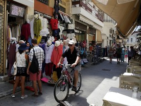 A man rides a bicycle at the Plaka tourist district of Athens, Tuesday, July 7, 2015. This is Greek tourism - July 2015 style - as the peak summer season in one of the world’s most popular destinations is glitched by a financial crisis of frightening proportions. (AP Photo/Spyros Tsakiris)