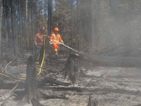 A ranger (L) and a soldier from the 3rd Canadian Division's Immediate Response Unit (West) help to extinguish a wildfire hot spot near Montreal Lake, Sask., in a photo released by the Canadian Forces July 9, 2015.   REUTERS/Canadian Forces/MCpl Melanie Ferguson/Handout