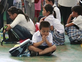 A boy sits on the floor as he waits with other students for the morning flag ceremony at a school in Manila. At another school, officials say over 1,000 students became ill after eating fruit-flavoured candy sold by vendors during recess. REUTERS/Romeo Ranoco/Files