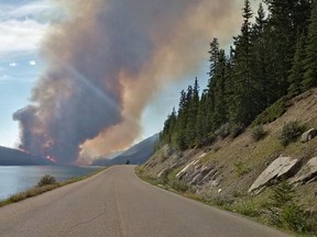 A wildfire rises over a hill in Jasper National Park on Thursday July 9, 2015. An evacuation of part of Jasper National Park has been ordered due to a forest fire in the picturesque Maligne Valley. (THE CANADIAN PRESS)