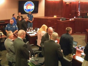 In this image taken from Colorado Judicial Department video, Colorado theatre shooter James Holmes, upper left in blue shirt, joins others in standing as the jury, not pictured, is brought into the courtroom, during Holmes' trial in Centennial, Colo., Friday, July 10, 2015. Colorado Judicial Department via AP, Pool