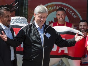 Canadian Prime Minister Stephen Harper, centre, stands with Federal Minister for Sport Bal Gosal, left, as he visits Canadian athletes for a photo opportunity at the 2015 Toronto Pan Am Games athletes' village in Toronto on Friday, July, 10 2015. THE CANADIAN PRESS/Chris Young