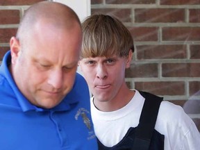 In this June 18, 2015, file photo, Charleston, S.C., shooting suspect Dylann Storm Roof, center, is escorted from the Sheby Police Department in Shelby, N.C. FBI director James Comey says Roof, the gunman in the Charleston church massacre should not have been allowed to purchase the gun used in the attack, and on July 10 attributed the problem to incomplete and inaccurate paperwork related to an arrest of Roof weeks before the shooting. (AP Photo/Chuck Burton, File)
