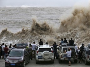 People look on as waves, under the influence of Typhoon Chan-hom, hit the shore in Wenling, Zhejiang province, China, July 10, 2015.  REUTERS/William Hong