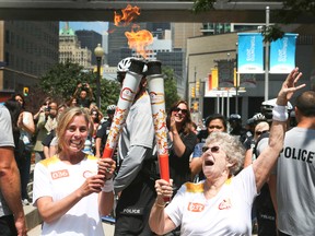 Katherine Cullen, left, hands the torch off to Marilyn Bell-Dilascio on July 10, 2015 on the final day of the Pan Am Games Torch Relay. (Veronica Henri/Toronto Sun)