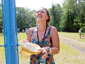 Folk Festival volunteer Giselle Duesterdiek finds relief from the heat by cooling off under an outdoor shower set up on the grounds of the annual Winnipeg Folk Fest on Saturday, July 11, 2015 at Birds Hill Provincial Park located just outside Winnipeg, Man. According to Environement Canada, the temperature hit 28 Celsius. (Brook Jones/Selkirk Journal/Postmedia Network)