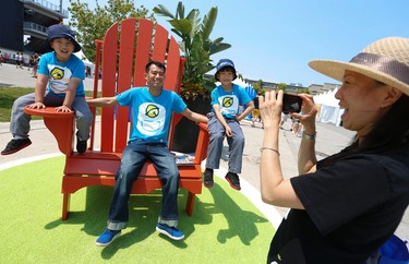Janice Lai of Toronto takes pictures of her husband and two children on a massive Muskoka chair at Pan Am Park at Exhibition Centre on Day One of the Games on Saturday July 11, 2015. Jack Boland/Toronto Sun/Postmedia Network