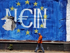 A man walks past graffiti in Athens, Greece July 12, 2015. Euro zone leaders will fight to the finish to keep near-bankrupt Greece in the euro zone on Sunday after the European Union's chairman cancelled a planned summit of all 28 EU leaders that would have been needed in case of a "Grexit". REUTERS/Cathal McNaughton