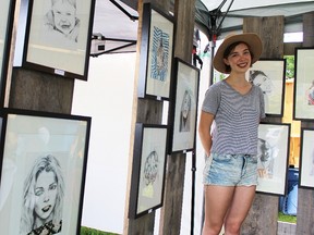 Chatham-Kent artist Ada Marie Bierling, 16, stands with some of her sketches at Art in the Park in Petrolia Saturday. Bierling, 16, one of 60 artists at the showcase, recently started her business, Illustrations by Ada Marie. (Tyler Kula, The Observer)