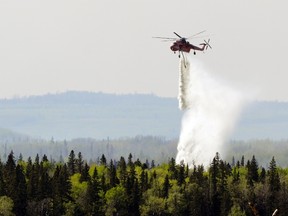A helicopter water bomber drops a load of water on a spot fire near Slave Lake, Alberta May 17, 2011. REUTERS/Todd Korol