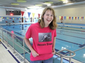 Jenna Gregg, who is swimming the equivalent of the distance from Kingston to the Vancouver aquarium to raise money for its marine mammal rescue centre, shows off her special t-shirt at the Artillery Park pool in Kingston, Ont. on Tues., July 7, 2015. Michael Lea/The Whig-Standard/Postmedia Network