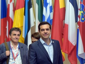 Greece's Prime Minister Alexis Tsipras, centre, and Greek Finance Minister Euclid Tsakalotos, left, leave a euro zone leaders summit in Brussels, Belgium, on July 13, 2015. Euro zone leaders clinched a deal with Greece on Monday to negotiate a third bailout to keep the near-bankrupt country in the euro zone after a whole night of haggling at an emergency summit. (REUTERS/Eric Vidal)