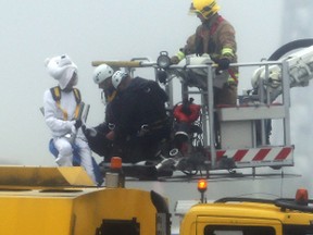 Emergency service workers talk to an activist, dressed as a teddy bear, top left, from the pressure group Plane Stupid, who was one of several demonstrators who occupied the north runway at London's Heathrow Airport to launch a protest on July 13, 2015. (Steve Parsons/PA via AP)