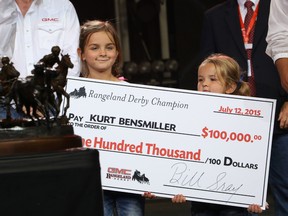 Kurt Bensmiller’s daughters Harlee and Hayze hold up his winning cheque as he repeats as the champion of the Rangeland Derby chuckwagon races at the Calgary Stampede in Calgary on Sunday July 12.