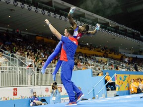 Cuba's coach Carlos Gil carries Manrique Larduet after the athlete's routine on horizontal bar during artistic gymnastics all-around competition in the Pan Am Games on July 13, 2015. (AP Photo/Gregory Bull)