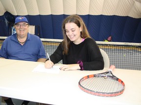 Carla White, right, looks over a copy of a document confirming her commitment to attend William Woods University in Fulton, Mo., on a tennis scholarship, while coach Paul Robert looks on, at the Sudbury Indoor Tennis Centre on Saturday.