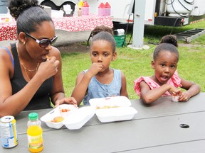 Kayela Riley enjoys some bridge fries with her two daughters, Amaira, 5, (middle) and Aliveah, 3 (right). The family were sitting in front of Bluewater Bridge Fries on National French Fry Day on Monday.PHOTO TAKEN AT SARNIA, ONTARIO ON Monday, July 13, 2015. (CHRIS O’GORMAN/ SARNIA OBSERVER/ POSTMEDIA NETWORK)