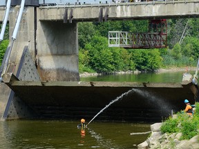 A diver sprays down one of the doors of the Springbank Dam. (MORRIS LAMONT, The London Free Press)