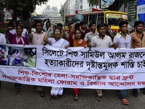 Bangladeshi protesters carry a banner during a demonstration against the lynching of a 13-year-old boy in Dhaka on July 14, 2015.  Outrage over the lynching of a 13-year-old boy mounted in Bangladesh July 14, 2015, with more protests over the murder which was captured on video, as one of the suspects confessed after being arrested in Saudi Arabia. Bangladeshi police have now arrested five people over the July 8 killing of Samiul Alam Rajon, who was tied to a pole and then subjected to a sickening assault in which he pleaded for his life. AFP PHOTO/ Munir uz ZAMAN