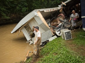 Robbie Taylor, left, stares at the swollen creek which destroyed the trailer he shares with his girlfriend Markita Trent, right, after deadly flooding in Flat Gap, Ky., Tuesday, July 14, 2015. Flash floods in northern Johnson County outside of Paintsville destroyed homes and vehicles and residents were reported missing a day after the floods. AP Photo/David Stephenson