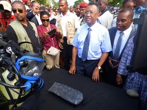 Madagascar's president Hery Rajaonarimampianina (2nd R) stands in front of a 50-kilogramme (110-pound) silver bar which was allegedly recovered by Marine archaeologist Barry Clifford in the wreck of William Kidd’s ship on May 7, 2015 on the Island of Sainte Marie. A team of American explorers claimed to have discovered silver treasure from the infamous 17th-century Scottish pirate William Kidd in a shipwreck off the coast of Madagascar. AFP PHOTO/Manjakahery Tsiresena