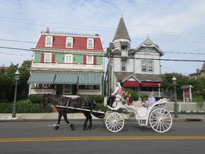 This June 26, 2015 photo shows visitors taking a horse carriage tour of Cape May, N.J. The city's hundreds of Victorian homes constitute what the National Historic Landmarks program calls “one of the largest collections of 19th century frame buildings” in the United States. Their gables, towers, domes, arched windows and inviting front porches, often trimmed in bright colors, create charming and whimsical streetscapes.  (AP Photo/Beth J. Harpaz)