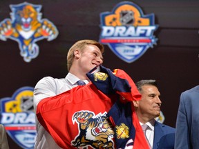 Lawson Crouse puts on a team jersey after being selected as the number eleven overall pick to the Florida Panthers in the first round of the 2015 NHL Draft at BB&T Center. (Steve Mitchell, USA TODAY Sports)