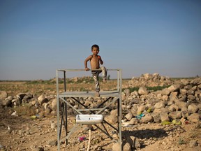 A Syrian refugee child eats a tomato while standing on a broken water point at an informal tent settlement near the Syrian border on the outskirts of Mafraq, Jordan, Sunday, July 12, 2015. (AP Photo/Muhammed Muheisen)
