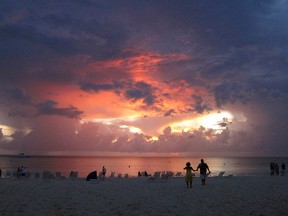 In this 2011 file photo, tourists walk on the Seven Mile Beach at sunset in George Town, Cayman Islands. Police say divers found a cement block with attached handcuffs on the seafloor just off the beach. REUTERS/Gary Hershorn/Files