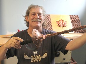 Ken Osborn, owner of Ozzy's Metal Magic in Kingston, Ont. on Thurs., July 9, 2015, holds up a sword he bronzed. He is retiring and moving out west. Michael Lea/The Whig-Standard/PostMedia Network
