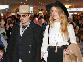 In this Jan. 26, 2015 file photo, U.S. actor Johnny Depp and Amber Heard arrive at Haneda international airport in Tokyo to promote his latest film "Mortdecai." Johnny Depp's wife Amber Heard has been charged with illegally bringing the couple's dogs to Australia. Prosecutors on Thursday, July 16, 2015 said that Heard was charged this week with two counts of illegally importing Pistol and Boo into Australia and one count of producing a false document. (AP Photo/Shizuo Kambayashi, File)