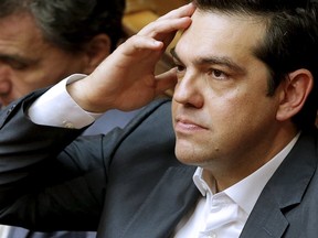 Greek Prime Minister Alexis Tsipras, right, reacts as he sits next to Finance Minister Euclid Tsakalotos during a parliamentary session in Athens, Greece July 16, 2015. The Greek parliament passed a sweeping package of austerity measures demanded by European partners as the price for opening talks on a multi-billion euro bailout package needed to keep the near-bankrupt country in the euro zone.   REUTERS/Christian Hartmann