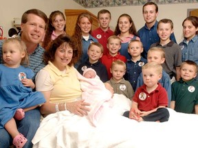 In this Aug. 2, 2007 file photo, Michelle Duggar, left, is surrounded by her children and husband Jim Bob, second from left, after the birth of her 17th child in Rogers, Ark. TLC is officially cancelling "19 Kids and Counting." The hit reality show "will no longer appear on the air," the network told The Associated Press on Thursday, July 15, 2015. The show had been in limbo since May after revelations that 27-year-old Josh Duggar molested five children including four of his sisters. (AP Photo/ Beth Hall, File)