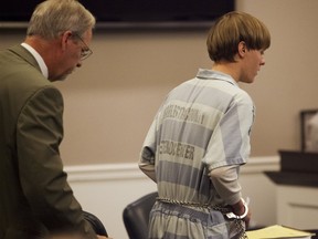 Dylann Roof, right, the 21-year-old man charged with murdering nine worshippers at a historic black church in Charleston last month, is helped to his chair by chief public defender Ashley Pennington during a hearing at the Judicial Center in Charleston, South Carolina July 16, 2015. REUTERS/Randall Hill