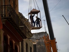 Workers in a metal box, hanging from a crane, remove the wall of a building that collapsed in Old Havana, Cuba, Thursday, July 16, 2015. Cuban officials say four people died in the Wednesday collapse, and a government statement published in Communist Party daily Granma says the two-story residence contained two family homes. AP Photo/Ramon Espinosa