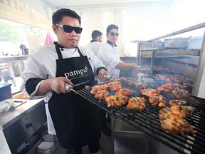 Pampas Brazilian Steakhouse Asst. Manager Archie Cailo takes out a tray of smoking BBQ meat at the opening day for Taste of Edmonton at Churchill Square in Edmonton, Alta., on Thursday July 16, 2015. Perry Mah/Edmonton Sun/Postmedia