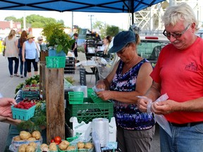 Marjan Pickering (left) of Awesome Berries and Gardens and Ross Garnham of Hyde’s Fruit Farm maneuver around their busy fruit and vegetable store at the Point Edward farmers’ market.  (CHRIS O'GORMAN, The Observer)