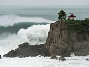 In this July 16, 2015 photo, waves crash against Katsurahama in Kochi on the island of Shikoku, western Japan, as a strong tropical storm sweeps across western Japan. Tropical Storm Nangka caused serious flooding Friday morning, July 17,  and disrupted air and train travel as it crossed the island of Shikoku and the main Japanese island of Honshu. (Kyodo News via AP)