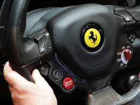 A visitor holds the steering wheel of the Ferrari 458 Spider during the second media day of the 82nd Geneva Auto Show at the Palexpo Arena in Geneva March 7, 2012. (REUTERS/Denis Balibouse)